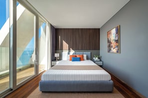 Une chambre à coucher moderne avec un grand lit, une table de chevet, une lampe et un tableau au mur.