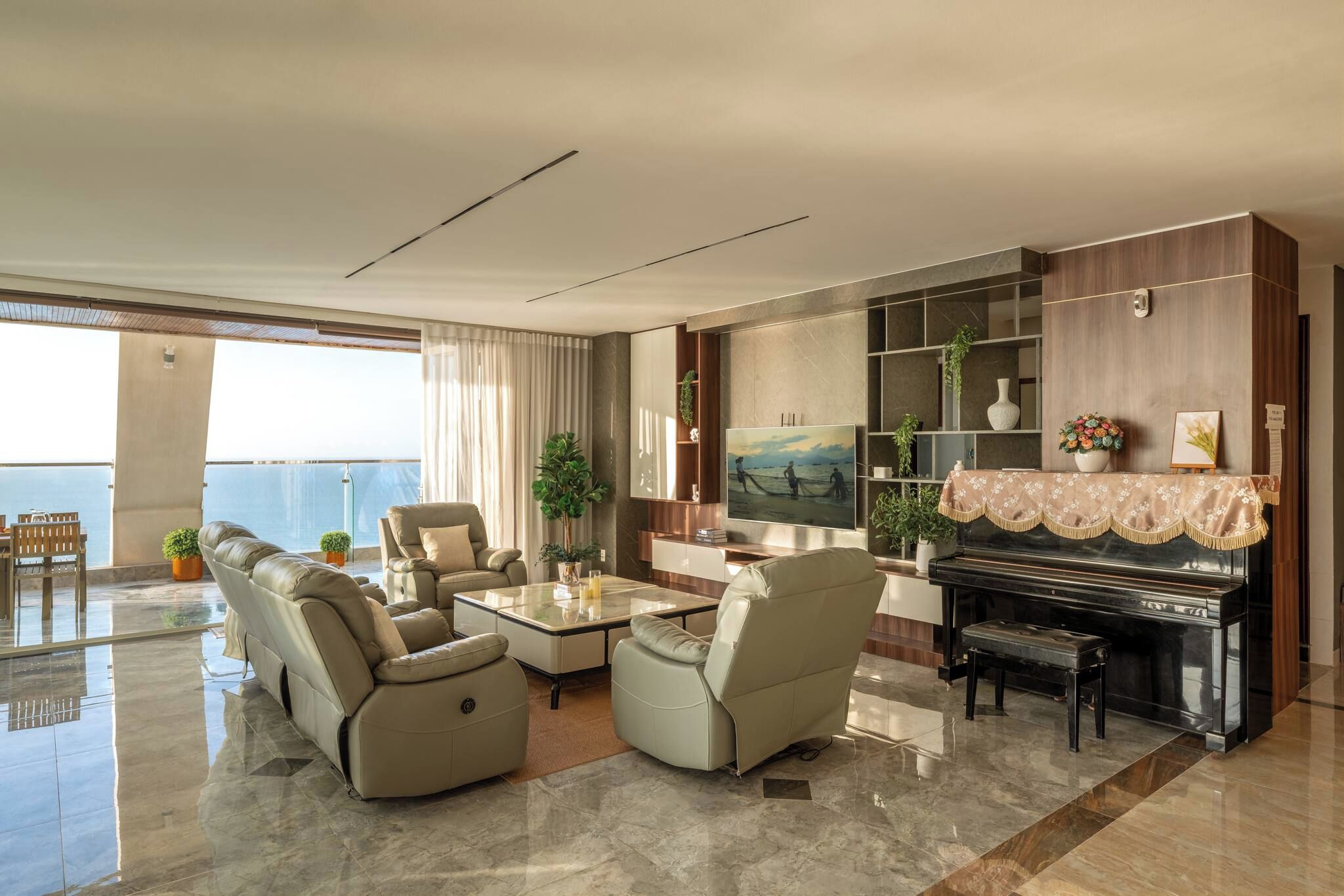 Ein geräumiges Wohnzimmer mit Klavier, bequemen Sitzgelegenheiten, Fernseher und Blick ins Freie.