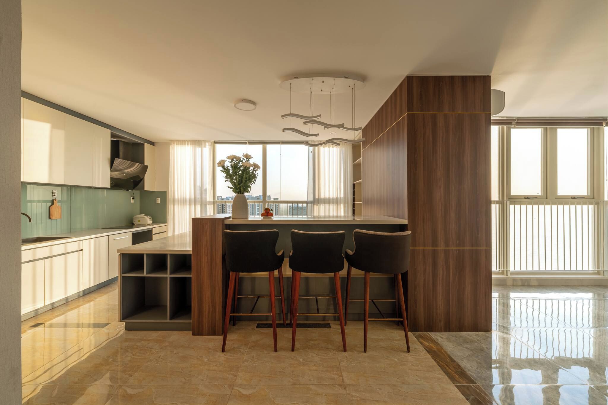A modern kitchen with a central island, bar stools, and a view of the city.