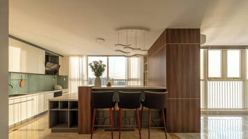 A modern kitchen with a central island, bar stools, and a view of the city.