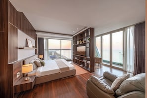 Habitación de hotel moderna con una cama grande, un sofá, un televisor y un balcón con vistas.