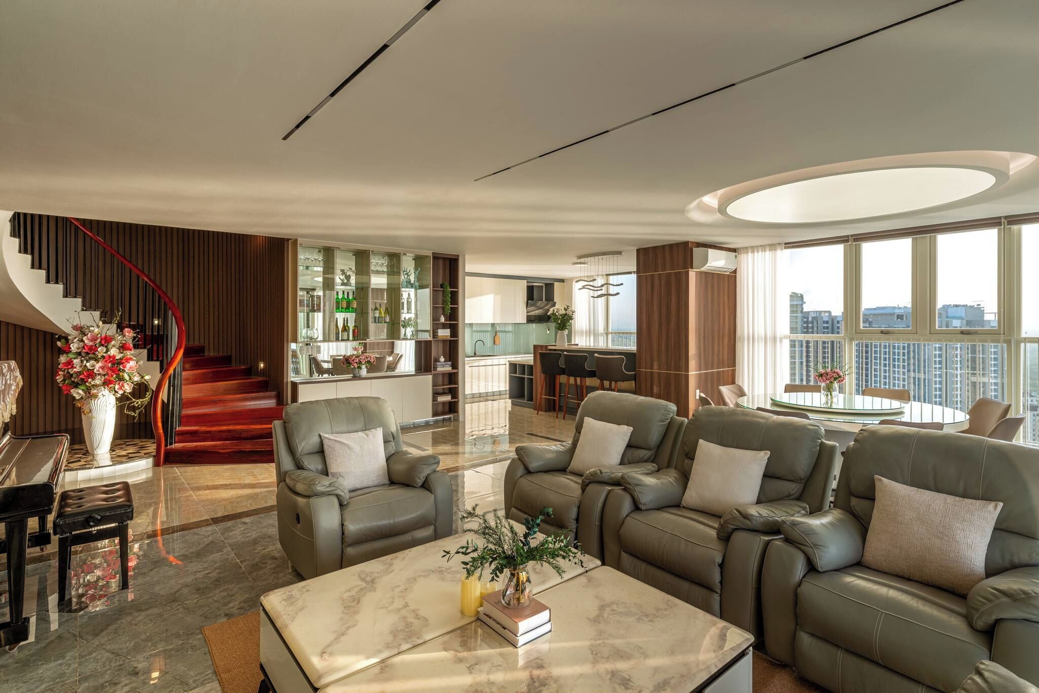 Ein modernes Wohnzimmer mit einem Marmortisch, Ledersofas und einer Treppe.