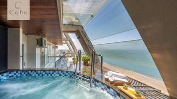 Une piscine avec vue sur la mer, un espace détente doté d’une balustrade en verre et un panneau indiquant le mot « Coho ».