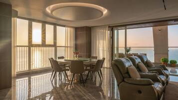 A modern interior with a dining area, a sofa, and large windows overlooking a body of water.
