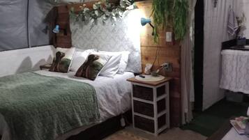 Une chambre à coucher avec un lit, une table de chevet, une lampe et des plantes suspendues.