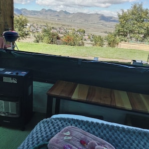 Una habitación con vistas a un paisaje montañoso, un banco de madera, una mesita y un calentador.