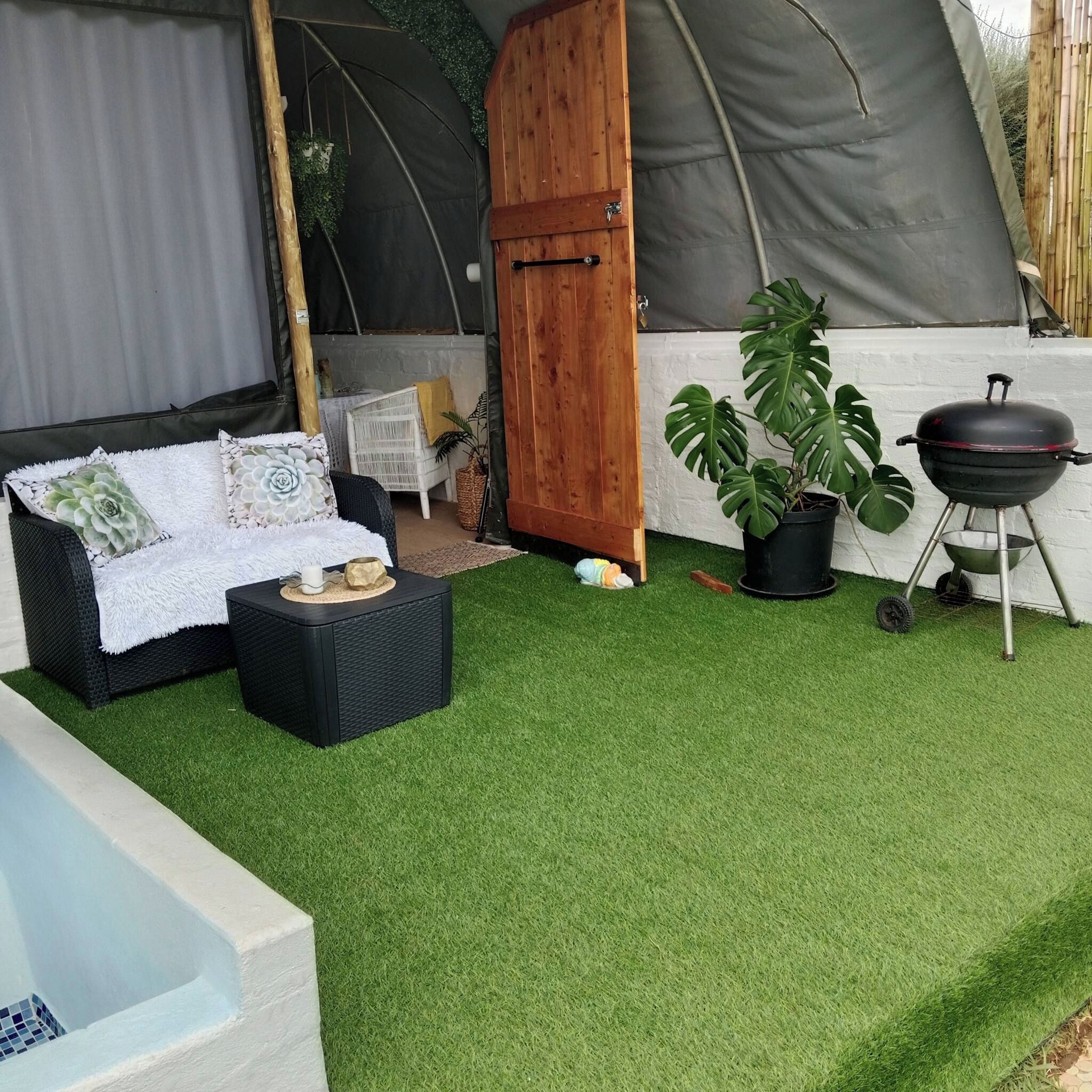 A tent with a white interior, a black grill, and a potted plant.