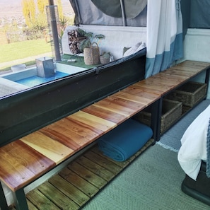 Una habitación pequeña con cama, banca y una mesita.