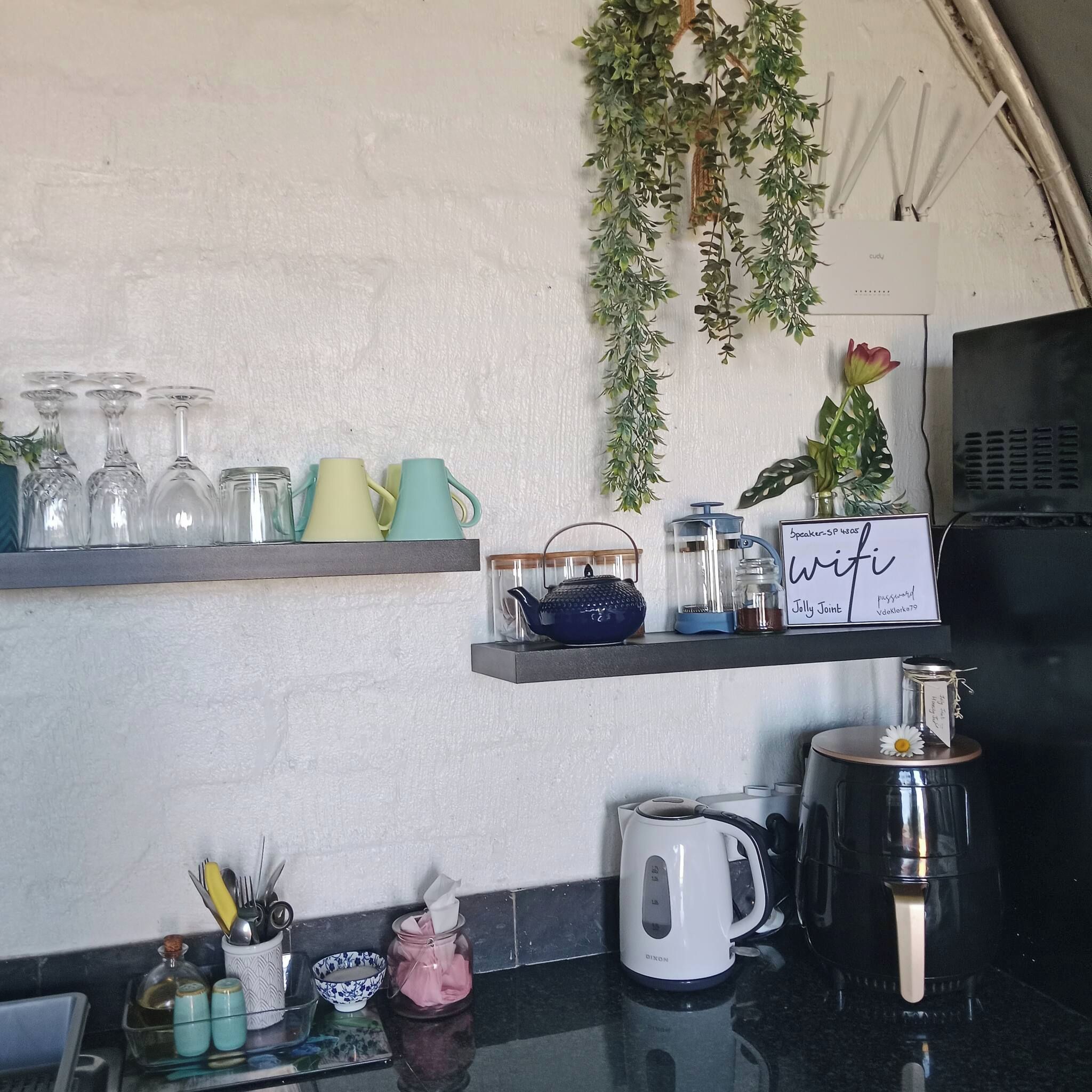 Eine Küche mit Regalen, auf denen Gläser, eine Kaffeemaschine und ein Namensschild stehen.