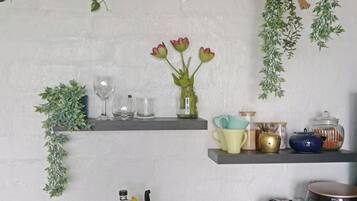 Eine Küche mit Regalen, auf denen Gläser, eine Blumenvase und verschiedene Küchenutensilien stehen.