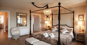 Un lit à baldaquin agrémenté d’un lustre, de lampes de chevet et d’un miroir mural.