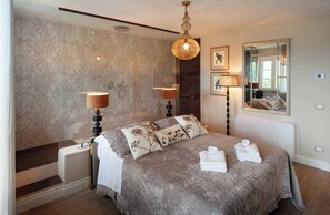 Ein Schlafzimmer mit einem Bett, zwei Nachttischlampen, einem Spiegel und einem Fenster.