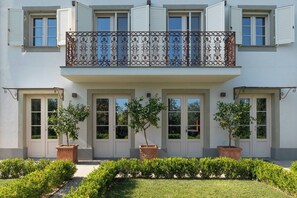 A two-story building with a balcony, multiple doors, and potted plants. - Villa Asti a luxury villa for enjoyment in Tuscany (Capannori)