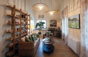 Un salon chaleureux avec un canapé, des meubles en osier, une table à manger et un coin cuisine avec une fenêtre.