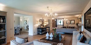 Ein geräumiges Wohnzimmer mit einem Kronleuchter, einer Couch, einem Couchtisch und einem Essbereich mit Stühlen.
