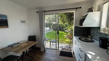 A modern kitchen with a sliding glass door leading to a garden.
