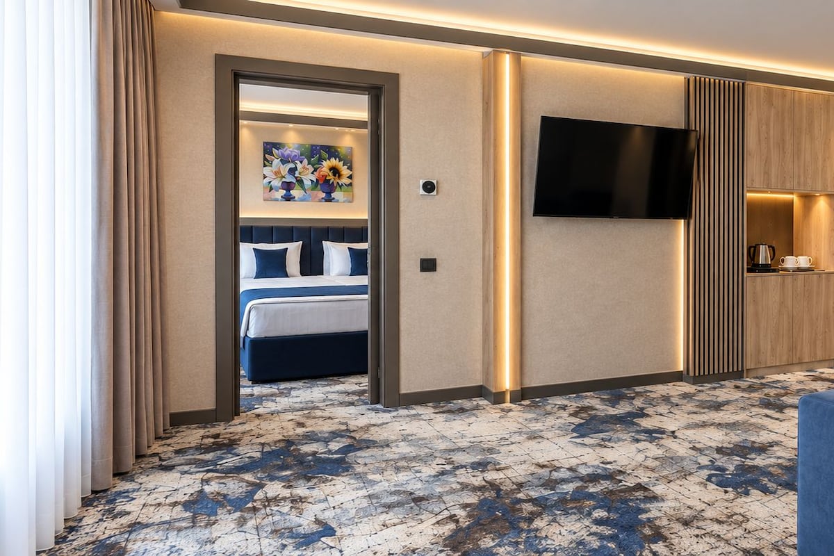 Una habitación de hotel con una cama, televisión, cafetera y sofá.