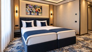 Una cama doble con un cabecero oscuro, un cuadro grande encima y una alfombra estampada.
