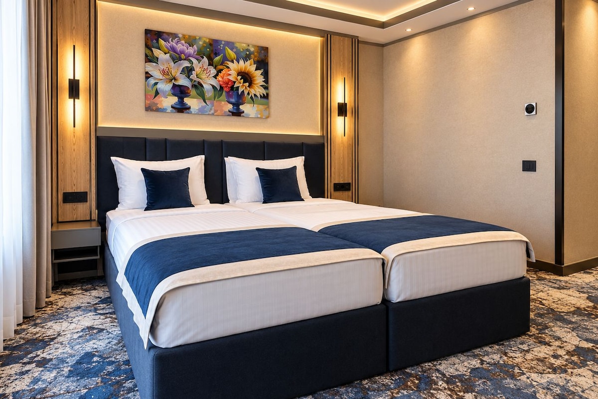Una cama doble con un cabecero oscuro, un cuadro grande encima y una alfombra estampada.