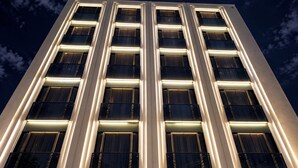 Un edificio de gran altura con varios pisos, que presenta un diseño arquitectónico moderno con ventanas iluminadas y fachada limpia.