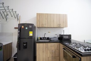 Eine kleine Küche mit Kühlschrank, Mikrowelle, Herd und Holzschränken.