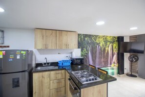 Eine moderne Küche mit Holzausstattung, einem Gasherd, einer Mikrowelle und einem Spülbecken.