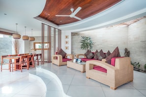 A modern living room with wicker furniture, a ceiling fan, and a view of the outdoors. - K Villa Seminyak by Premier Hospitality  (Seminyak)