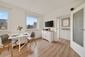 Eine moderne Küche mit Essbereich, einem Fernseher und Blick ins Freie.