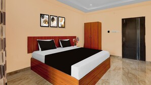 A modern hotel room with a wooden headboard, a large bed with black and white bedding, a wooden wardrobe, and a door with a handle. - OYO hotel O Beemli Beach Visakhapatnam (Visakhapatnam)