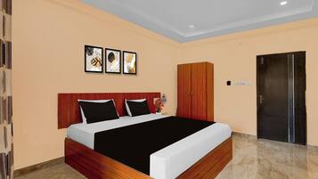 A modern hotel room with a wooden headboard, a large bed with black and white bedding, a wooden wardrobe, and a door with a handle.