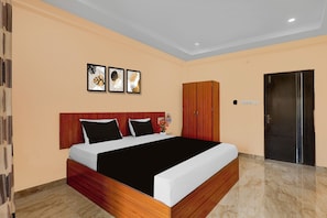 Quarto de hotel moderno com cabeceira de madeira, uma cama grande com roupa de cama preta e branca, um guarda-roupa de madeira e uma porta com puxador.