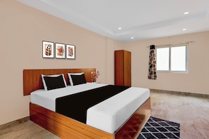 A hotel room with a large bed, a wardrobe, a window with curtains, and three framed pictures on the wall. - OYO hotel O Beemli Beach Visakhapatnam (Visakhapatnam)