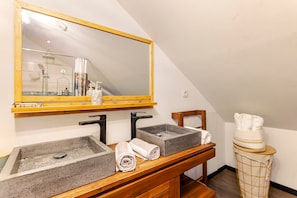 Une salle de bain dotée d’un grand miroir, de deux vasques avec des robinets modernes et d’un meuble-lavabo en bois.