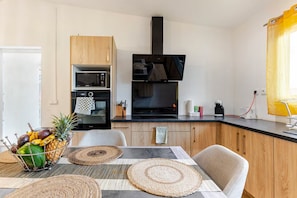 Une cuisine moderne avec des meubles en bois, un four encastré, un four à micro-ondes et une hotte noire.