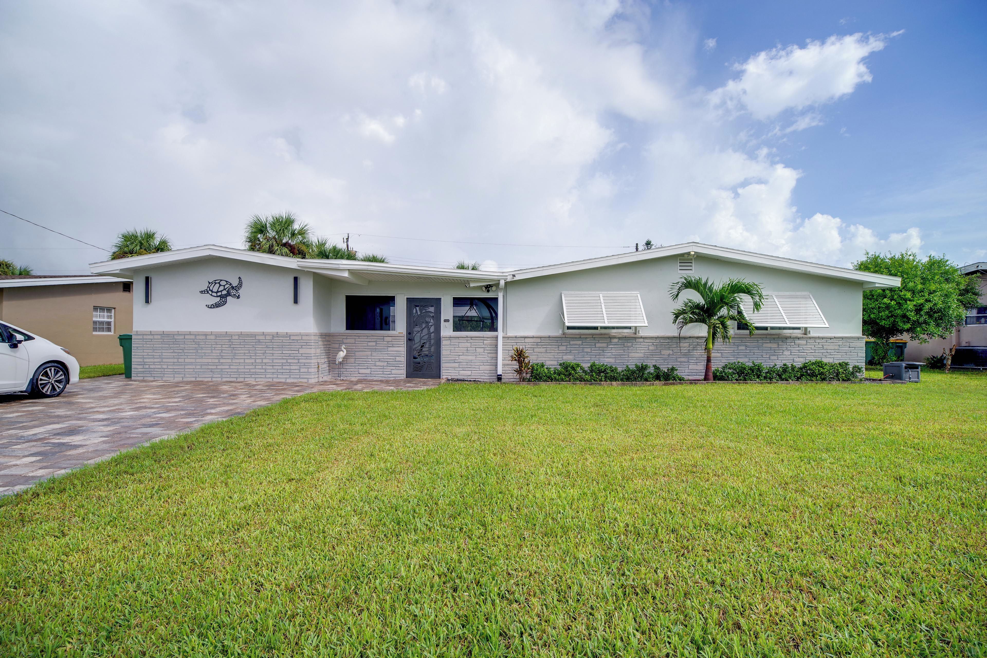 A modern two-story house with a flat roof, a front porch, and a well-maintained lawn.