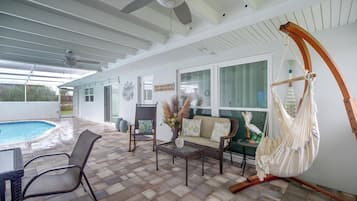 Un patio techado con piscina, mobiliario exterior y una hamaca.