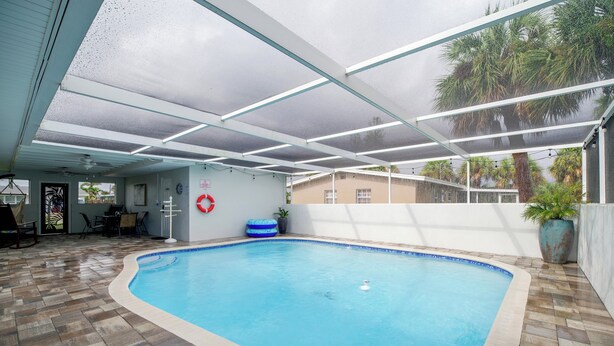 An indoor swimming pool with a tiled floor, a ceiling with glass panels, and a lifebuoy on the wall. - 1/2 Mi to Ocean! Couple's Haven in Satellite Beach (Satellite Beach)