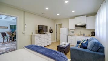 Un dormitorio moderno con cama, televisor, cómoda y kitchenette.