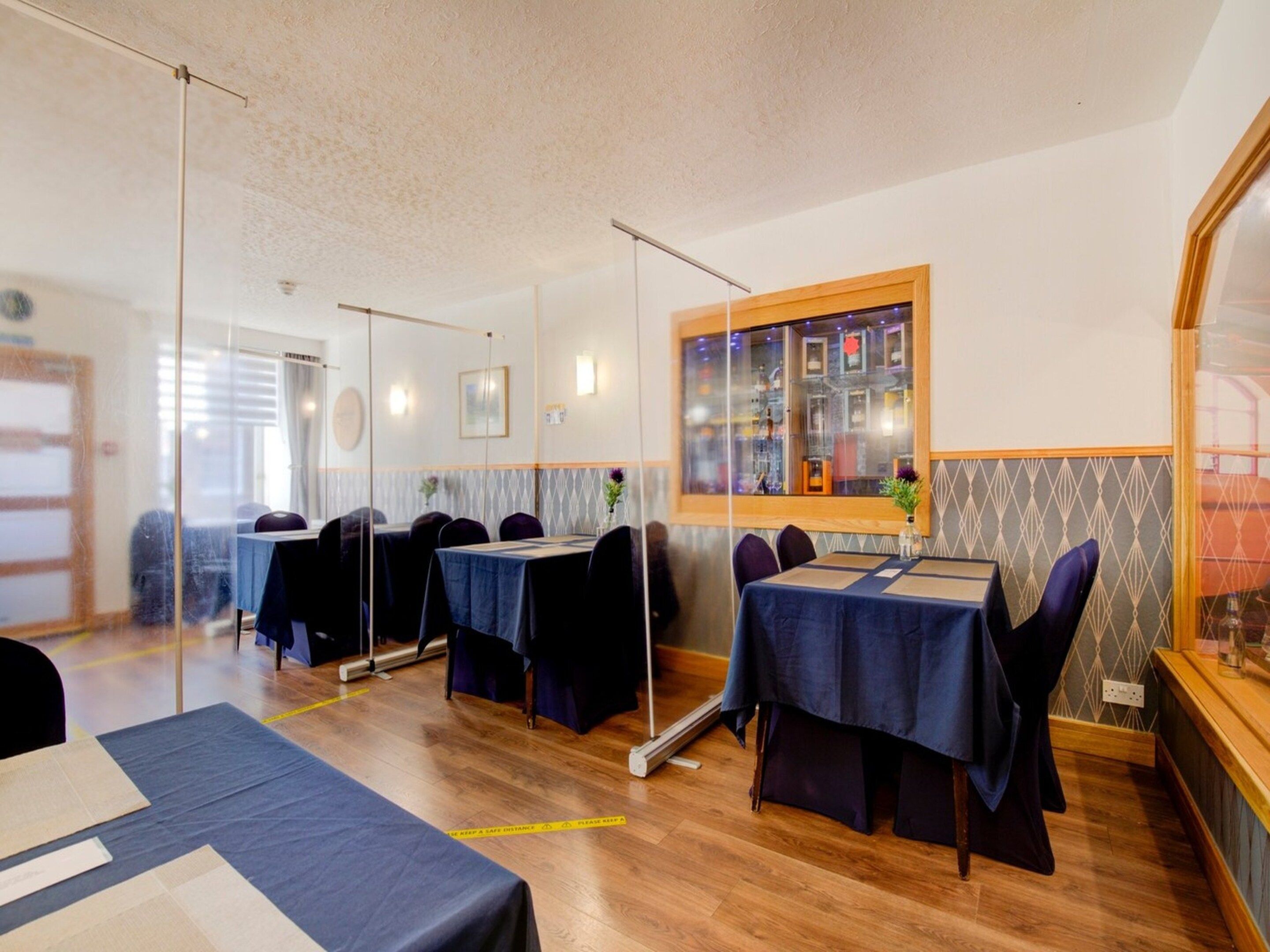A dining area with tables set for guests, a window with a view, and a wall-mounted light fixture.