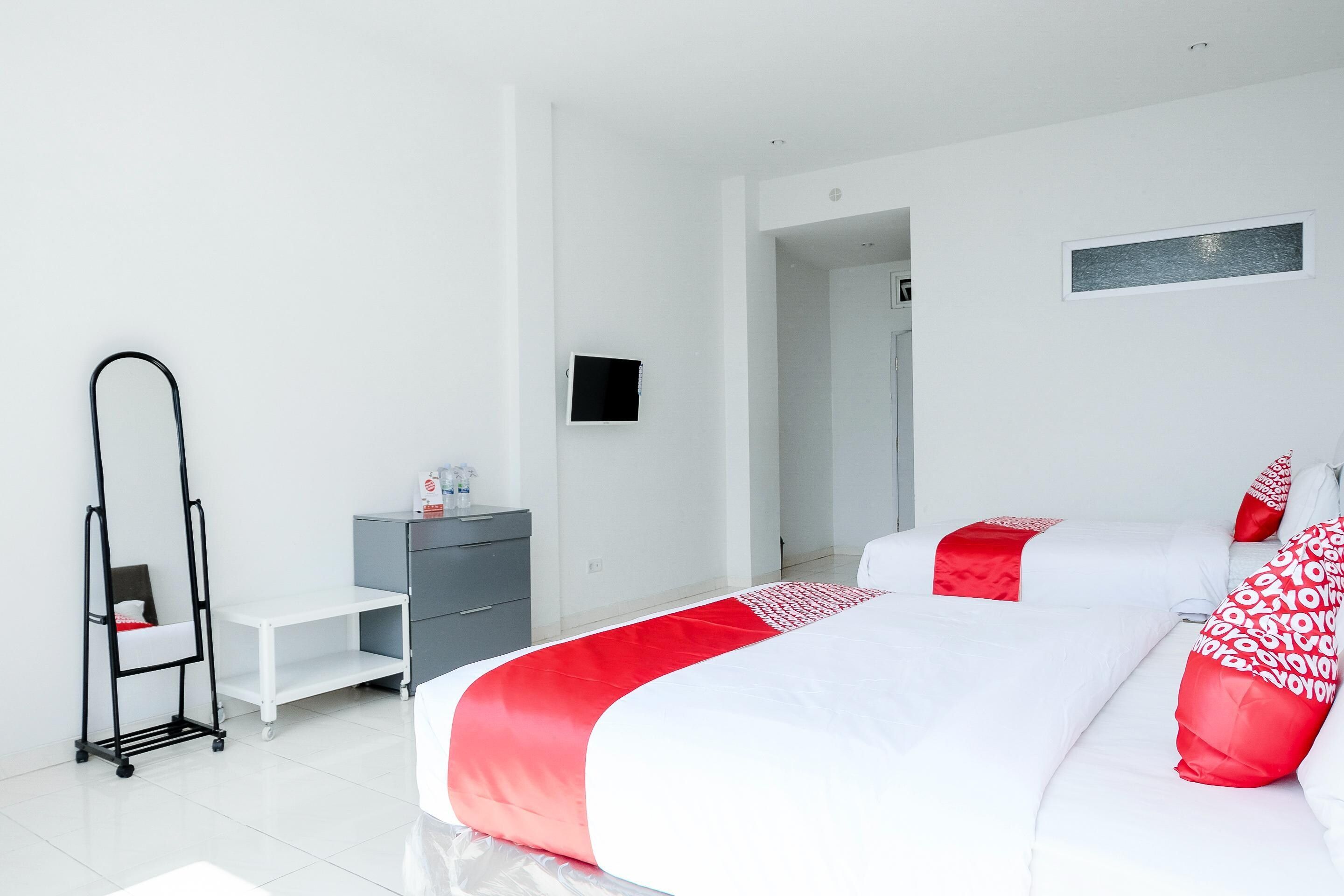 A modern hotel room with a bed, a desk, a wardrobe, and a mirror.