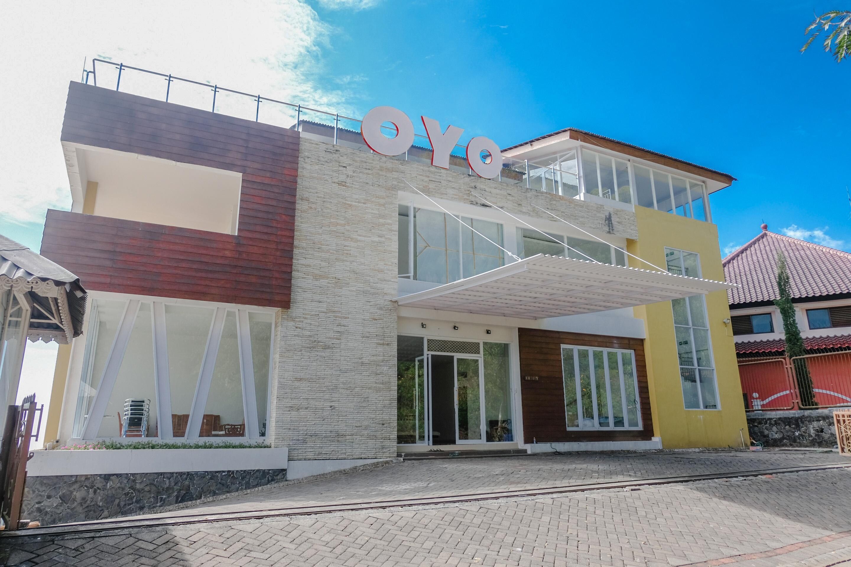 A modern building with a prominent 'OYO' sign, large windows, and a tiled roof.