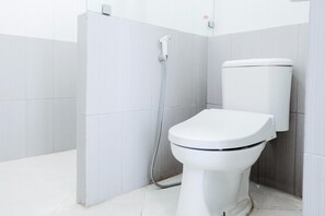 A modern bathroom with a white toilet, a shower, and a wall-mounted toilet tank. - Luxury Triple Suite W/ Free Wifi and Parking (Batu)