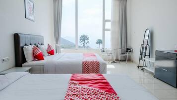 A hotel room with two beds, a desk, a chair, a dresser, and a large window with a view of the outdoors.