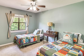 A bedroom with two beds, a ceiling fan, a window with curtains, a bedside table with a lamp, and a clock. - Fish & Hunt! Waterfront Home w/ Dock in Midway (Midway)