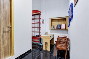 A compact room with a desk, chairs, a red ladder, and a shelf with items. - Spacious Triple Suite for Groups With Free Wifi (Yogyakarta)