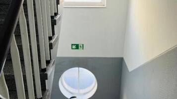 Eine Treppe mit einem Schachbrettmuster im Boden, einer weißen Brüstung und einem kleinen Fenster am oberen Ende.