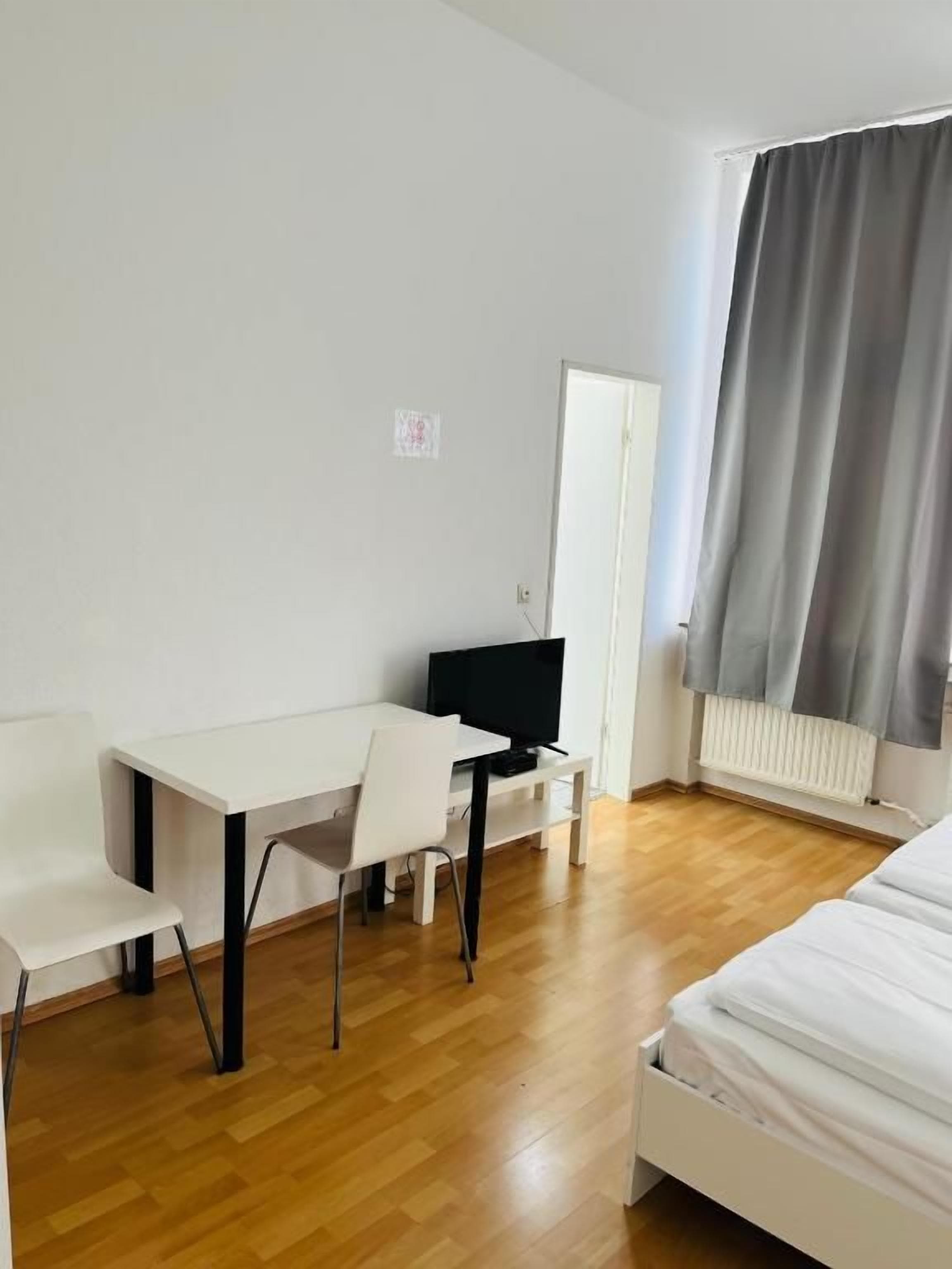 Ein Zimmer mit einem Bett, einem Schreibtisch, einem Stuhl und einem Fernseher.