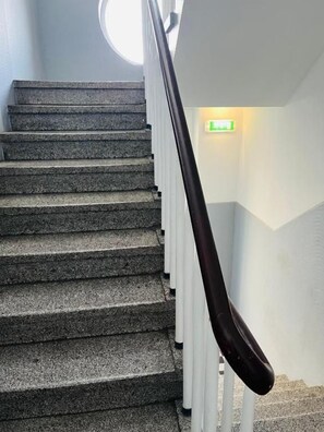 A staircase with a handrail and a green exit sign.