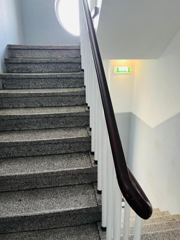 A staircase with a handrail and a green exit sign.