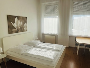 A hotel room with a bed, a desk, and a radiator.